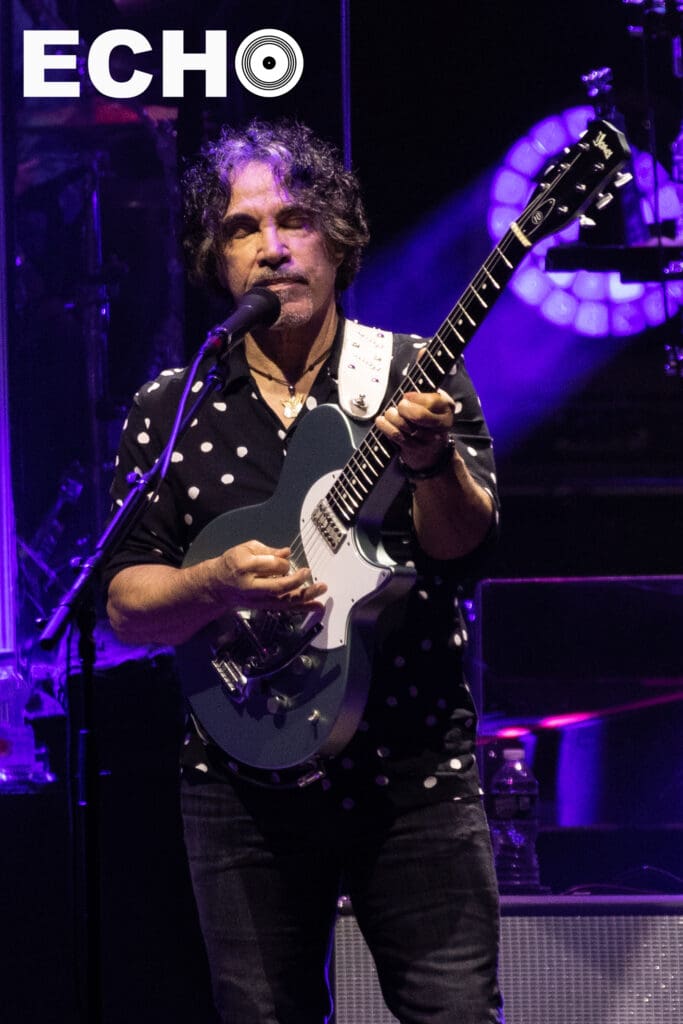 John Oates is feeling the music as he plays guitar with his eyes closed.