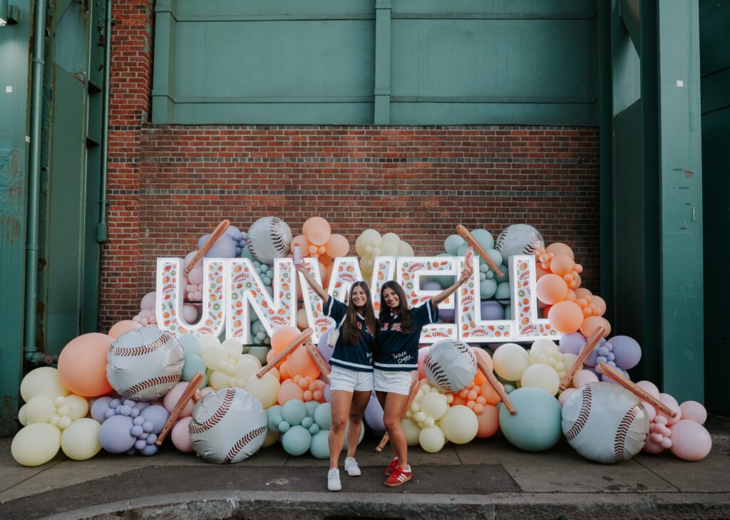 Fans pose in front of Unwell sign under the Green Monster