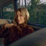 Hilary Duff poses in the back seat of an old car looking directly in the camera