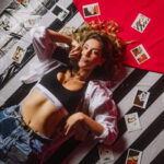 press photo of Natalie Shay laying on the floor surrounded by Polaroids